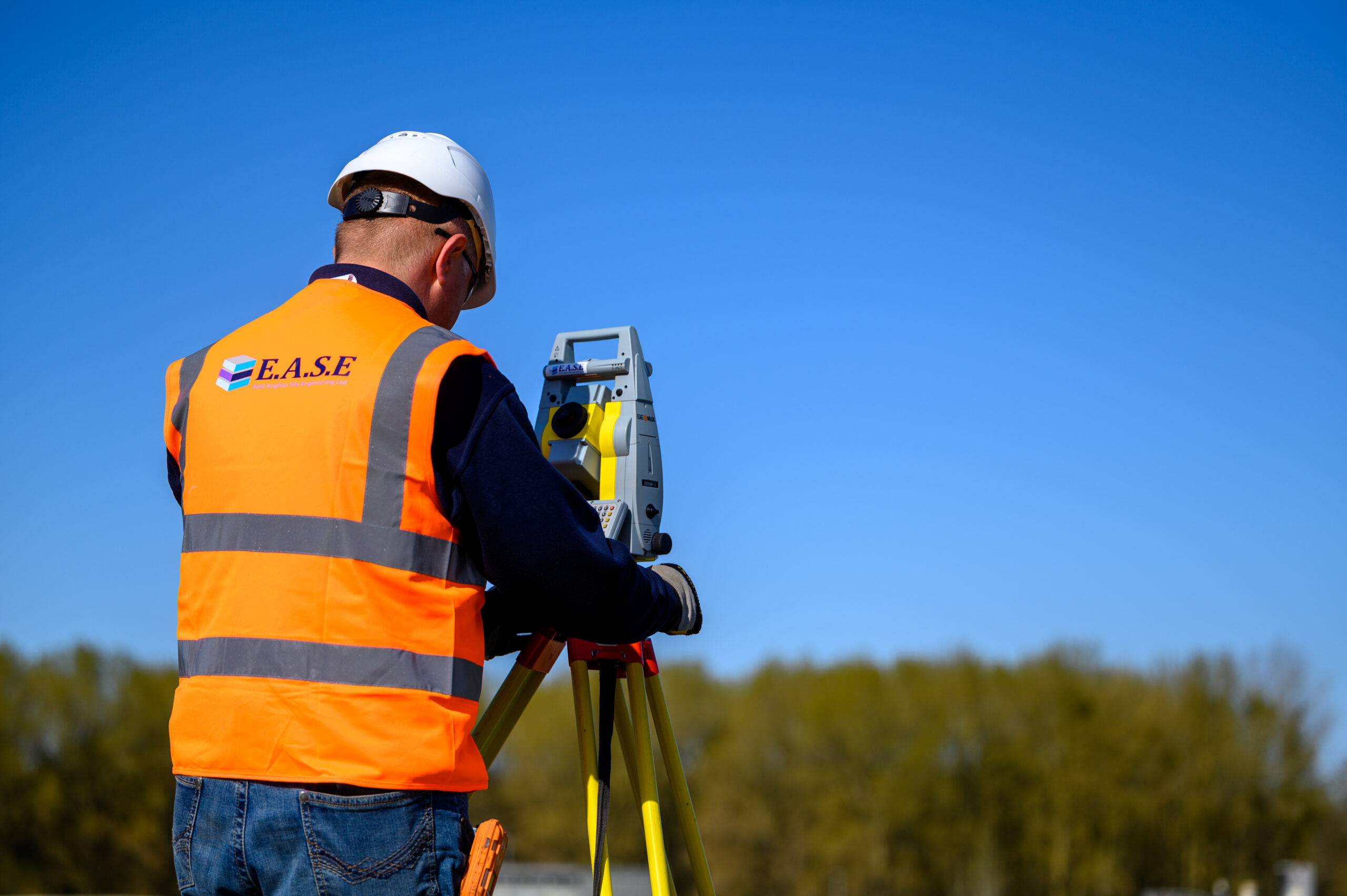 Site engineer operating surveying instrument on industrial site