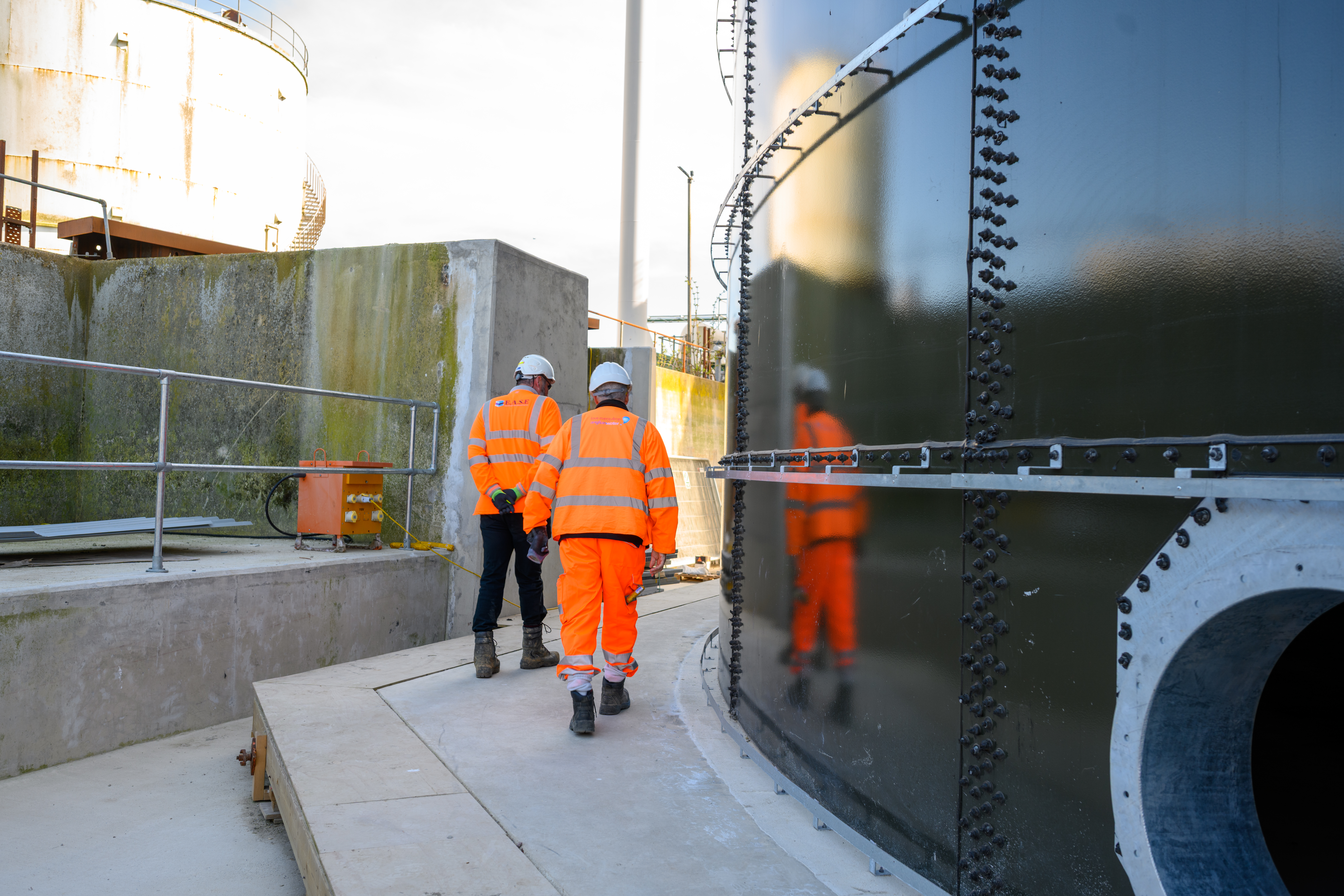 Site engineers walking alongside treatment tank at Whitlingham STC